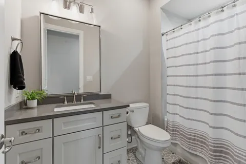 a bathroom with a granite countertop toilet sink and mirror