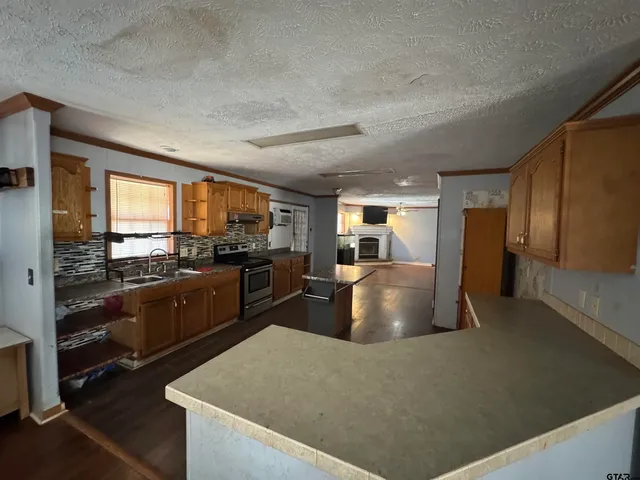 a kitchen with stainless steel appliances granite countertop a refrigerator a stove and a sink with wooden floor