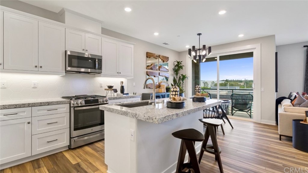 a kitchen with stainless steel appliances granite countertop a stove top oven a sink dishwasher and white cabinets with wooden floor