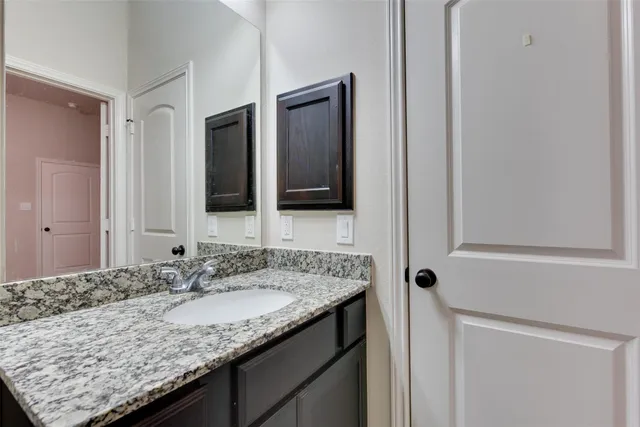 a bathroom with a granite countertop sink and a mirror