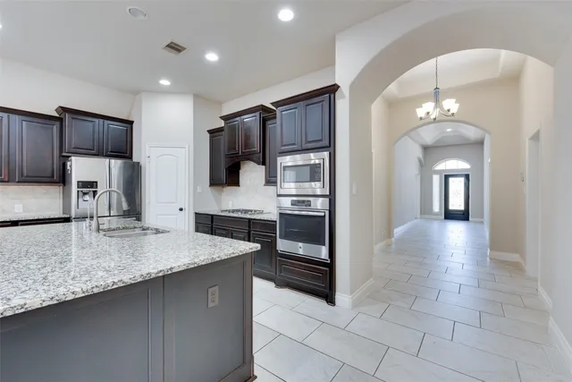 a kitchen with stainless steel appliances granite countertop a sink and a refrigerator
