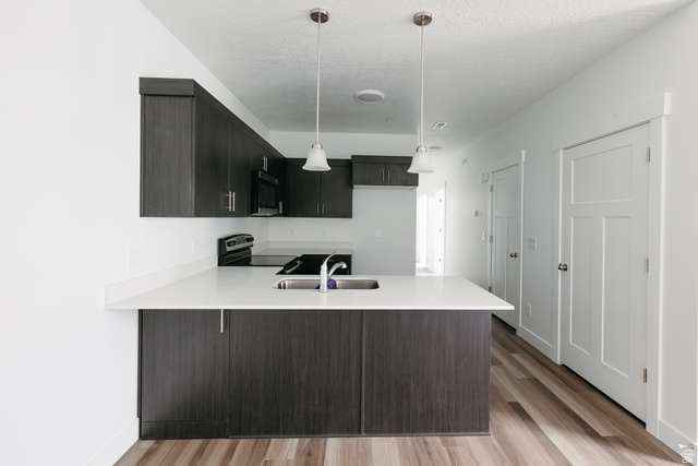 4653 South Alder Drive, Unit H303 Mapleton, UT 84664 - Photo 6 of 15 Kitchen featuring range with electric cooktop, a peninsula, light wood-style floors, modern cabinets, and a textured ceiling