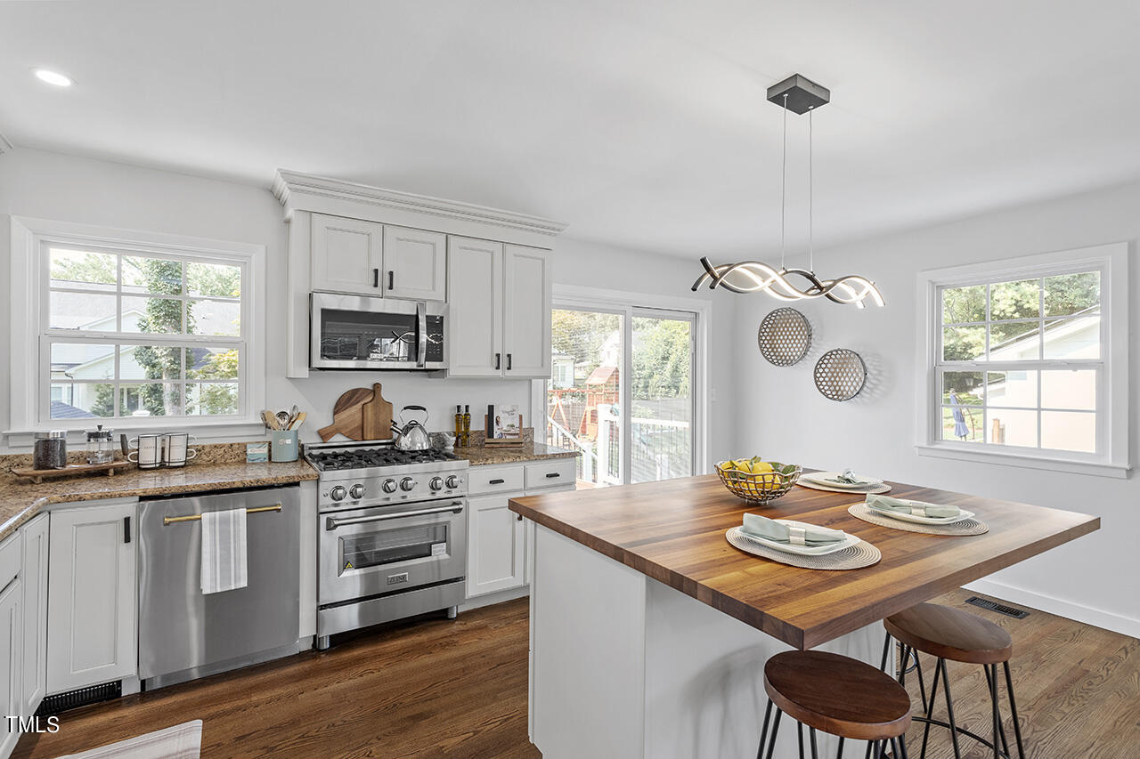 408 Latimer Road Raleigh, NC 27609 - Photo 7 of 19 a kitchen with stainless steel appliances kitchen island granite countertop a stove a sink a dining table and chairs