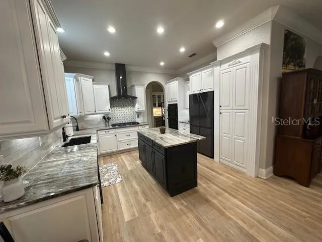 a large kitchen with stainless steel appliances kitchen island granite countertop a refrigerator and a sink