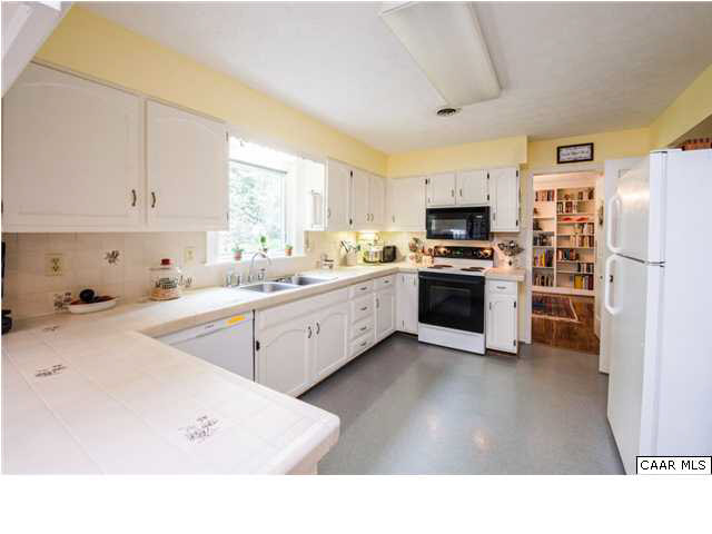 2713 Huntington Road Charlottesville, VA 22901 - Photo 5 of 17 a kitchen with stainless steel appliances a stove a sink a refrigerator a window and white cabinets