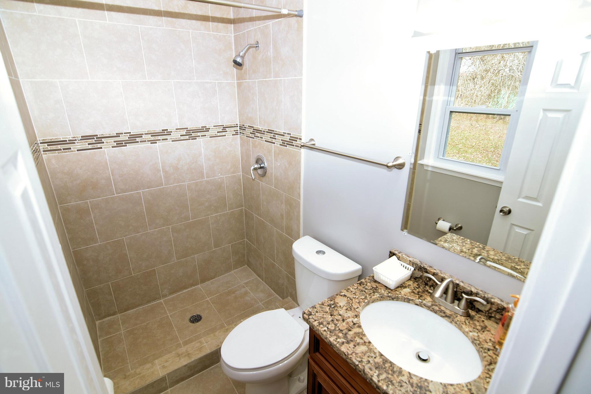 6504 Springbrook Lane Clinton, MD 20735 - Photo 21 of 30 a bathroom with a granite countertop sink toilet mirror vanity and shower