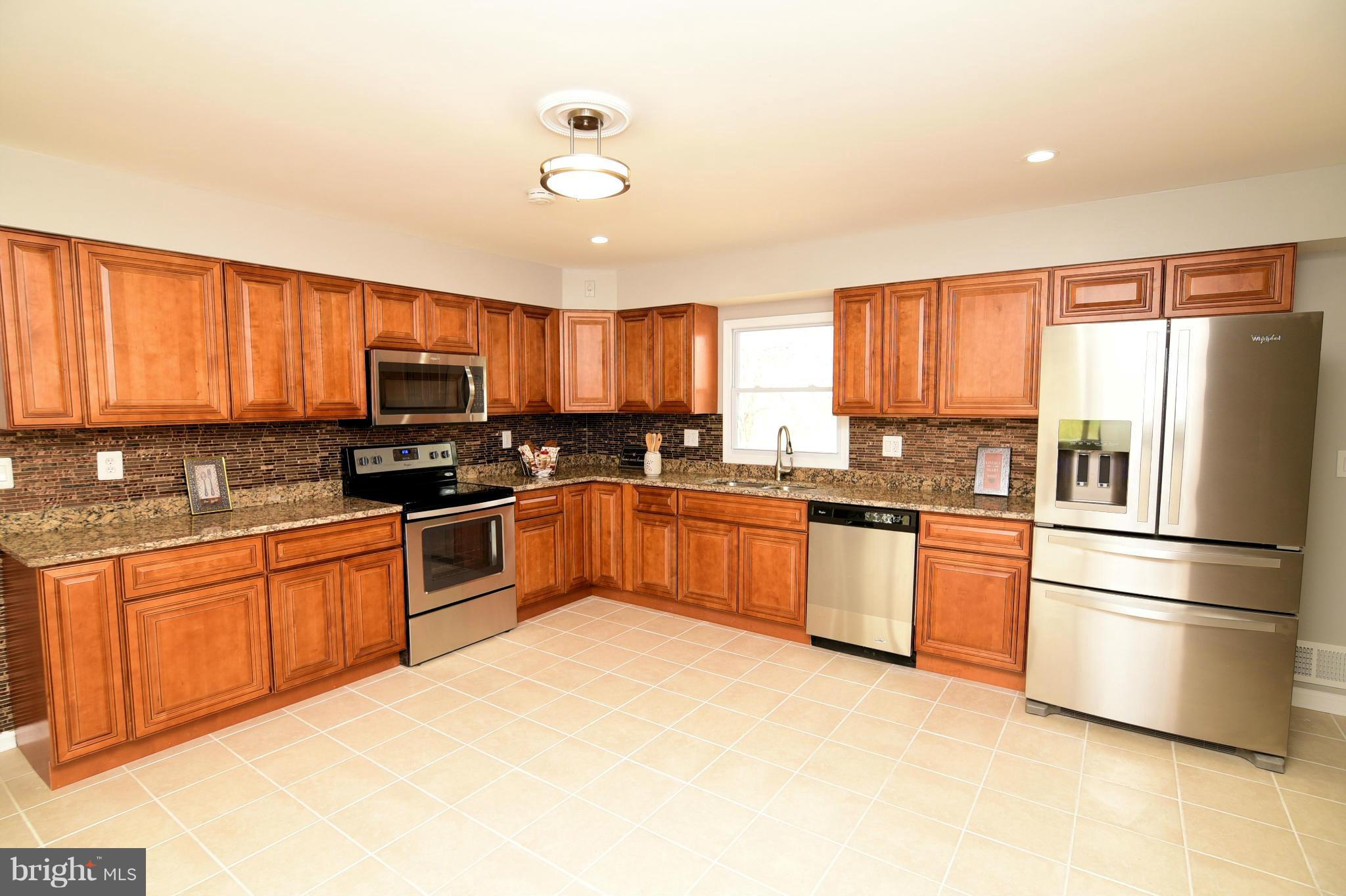 6504 Springbrook Lane Clinton, MD 20735 - Photo 6 of 30 a kitchen with granite countertop a refrigerator stove top oven a sink and dishwasher with wooden floor