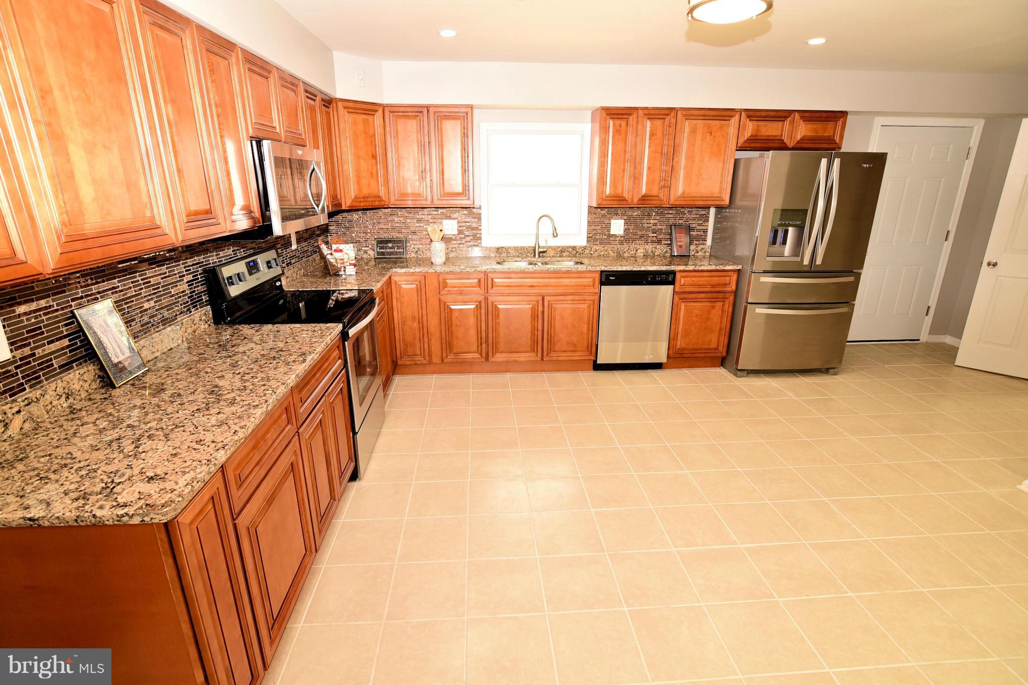 6504 Springbrook Lane Clinton, MD 20735 - Photo 7 of 30 a kitchen with stainless steel appliances granite countertop a sink a stove a refrigerator a washer dryer and a cabinets