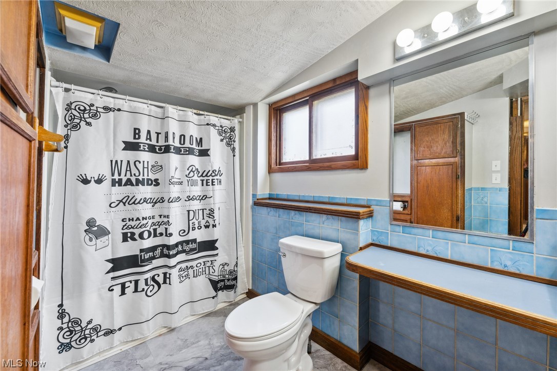 1470 Collar Price Road Hubbard, OH 44425 - Photo 18 of 23 Bathroom with tile floors, vaulted ceiling, toilet, and tile walls