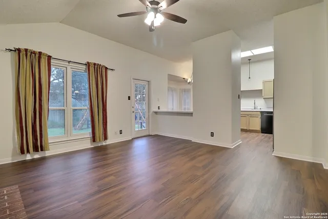 a view of an empty room with wooden floor and a window