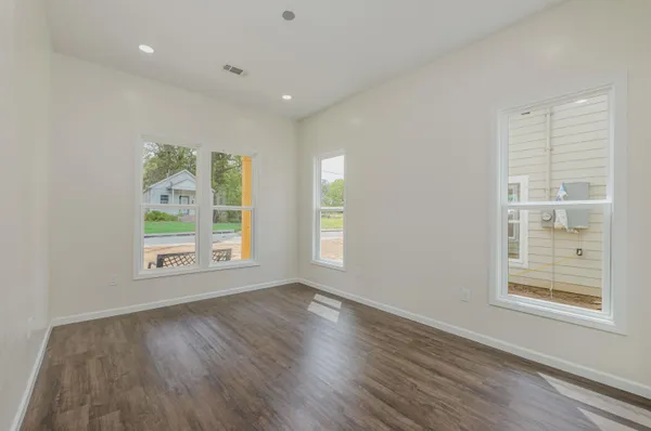 an empty room with wooden floor and windows