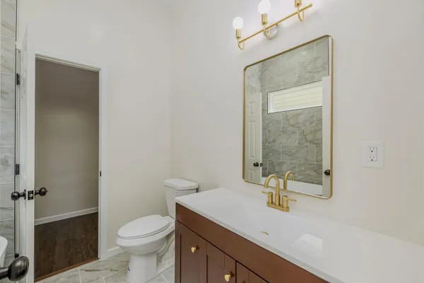 a bathroom with a granite countertop sink a toilet and a mirror