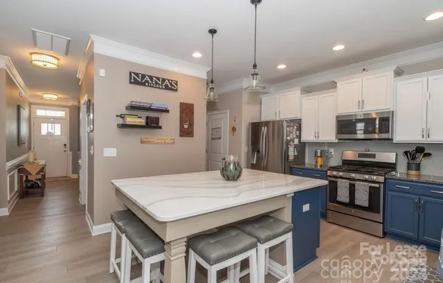 a kitchen with stainless steel appliances granite countertop a stove a refrigerator a kitchen island a sink and chairs