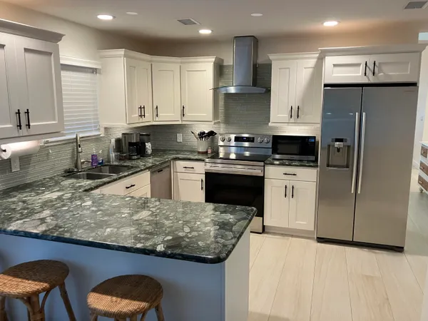 a kitchen with stainless steel appliances granite countertop a sink a stove a refrigerator and cabinets