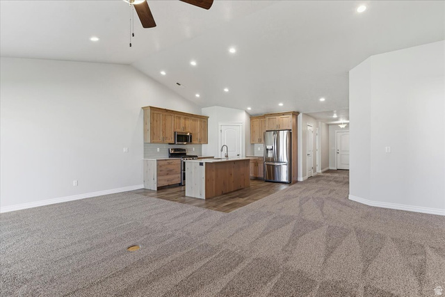 2028 West Grace Way Layton, UT 84041 - Photo 36 of 36 Kitchen featuring open floor plan, stainless steel appliances, dark colored carpet, a center island with sink, and ceiling fan