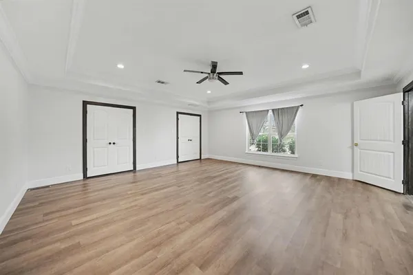 a view of an empty room with a window and wooden floor