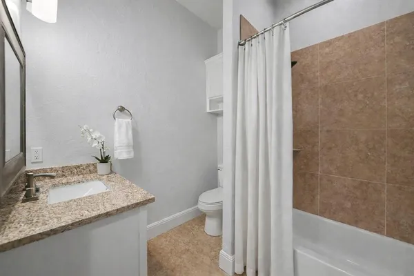 a bathroom with a granite countertop sink toilet and shower