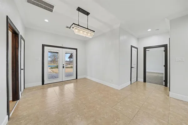 a view of an empty room and chandelier fan
