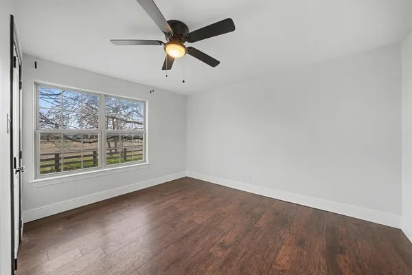 an empty room with wooden floor fan and windows