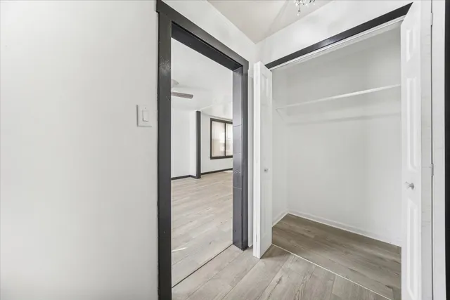 a view of a hallway with wooden floor and closet
