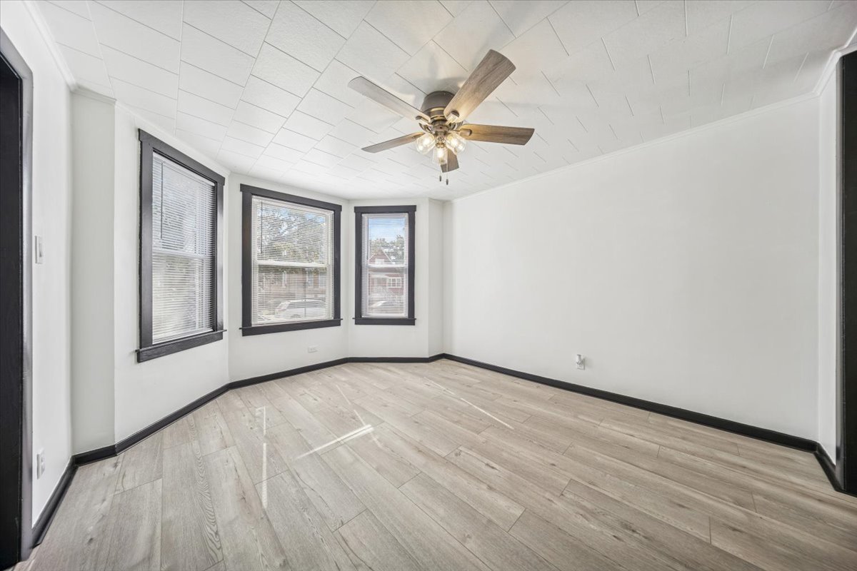3134 West 39th Place, Unit 1 Chicago, IL 60632 - Photo 4 of 16 an empty room with wooden floor fan and windows