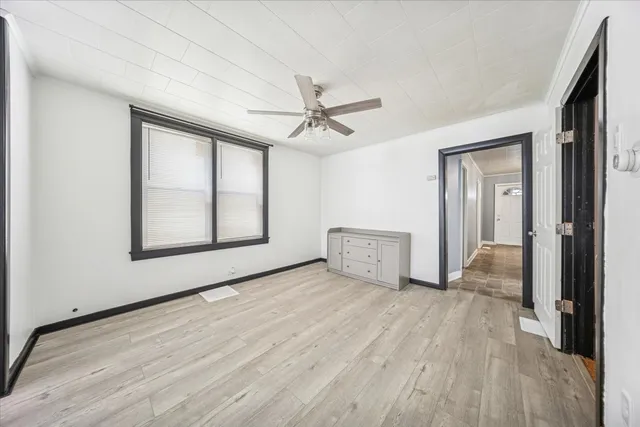 a view of an empty room with a window and wooden floor