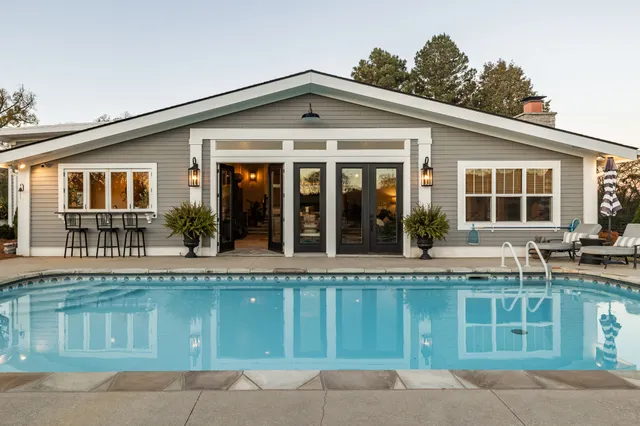 a view of a house with a swimming pool and sitting area