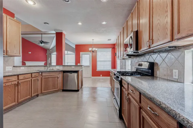 a kitchen with stainless steel appliances granite countertop a stove a sink and a microwave