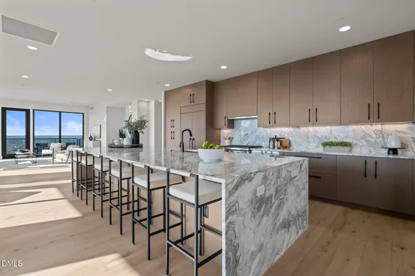 a kitchen with stainless steel appliances kitchen island granite countertop a table chairs sink and cabinets