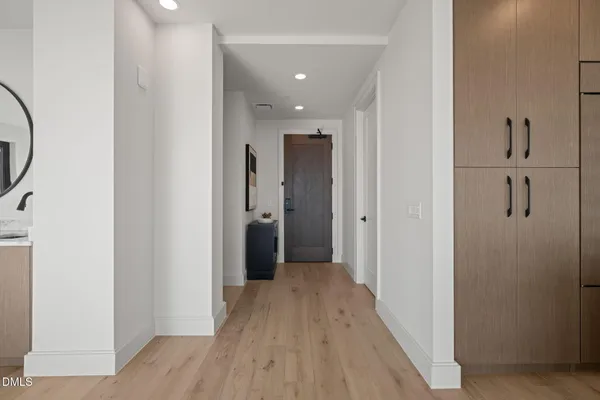 a view of a hallway with wooden floor and a bathroom