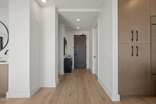 a view of a hallway with wooden floor and a bathroom