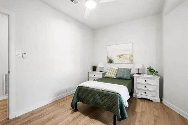 a bedroom with a bed and a lamp on dresser
