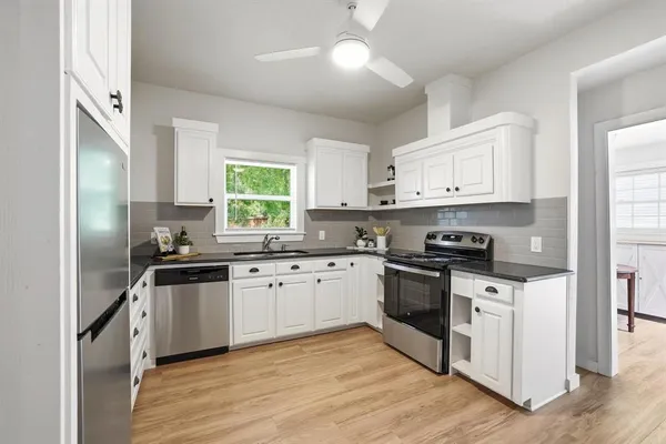 a kitchen with a refrigerator a stove a sink and white cabinets