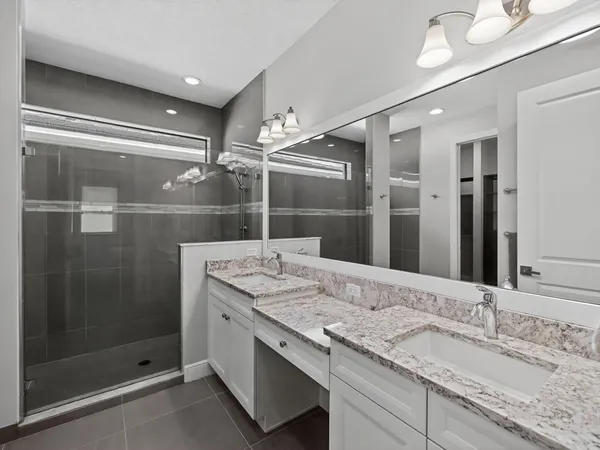 a bathroom with a granite countertop sink a mirror and shower