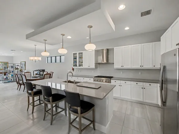 a kitchen with granite countertop a stove a sink a dining table and chairs with wooden floor