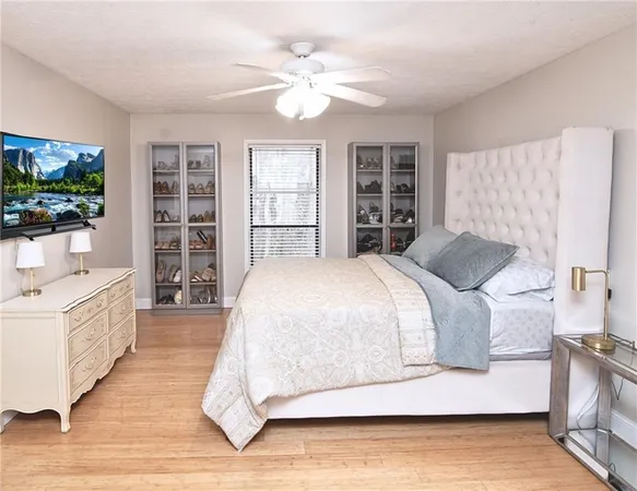 a spacious bedroom with a large bed a flat screen tv and a book shelf