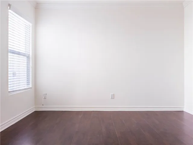 an empty room with wooden floor and window