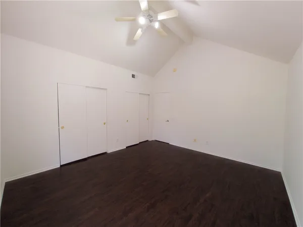 an empty room with wooden floor and fan