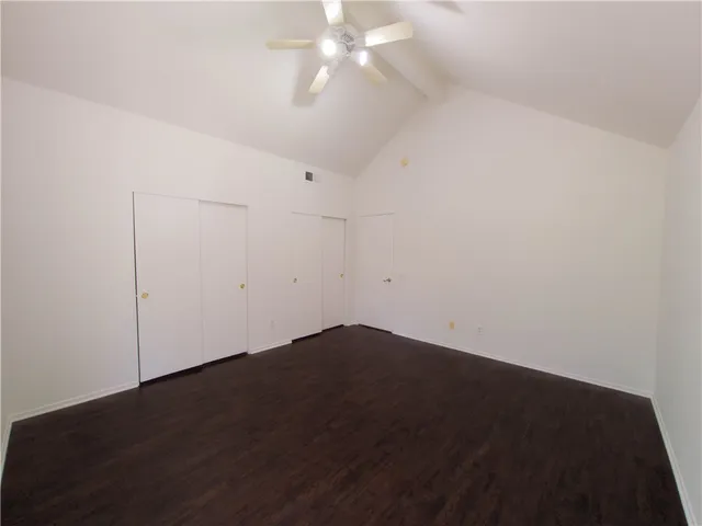 an empty room with wooden floor and fan