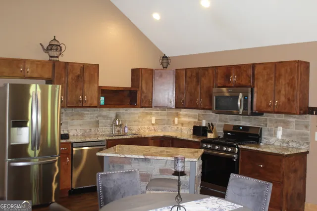 a kitchen with stainless steel appliances granite countertop a stove a sink dishwasher a refrigerator oven and a cabinets with wooden floor