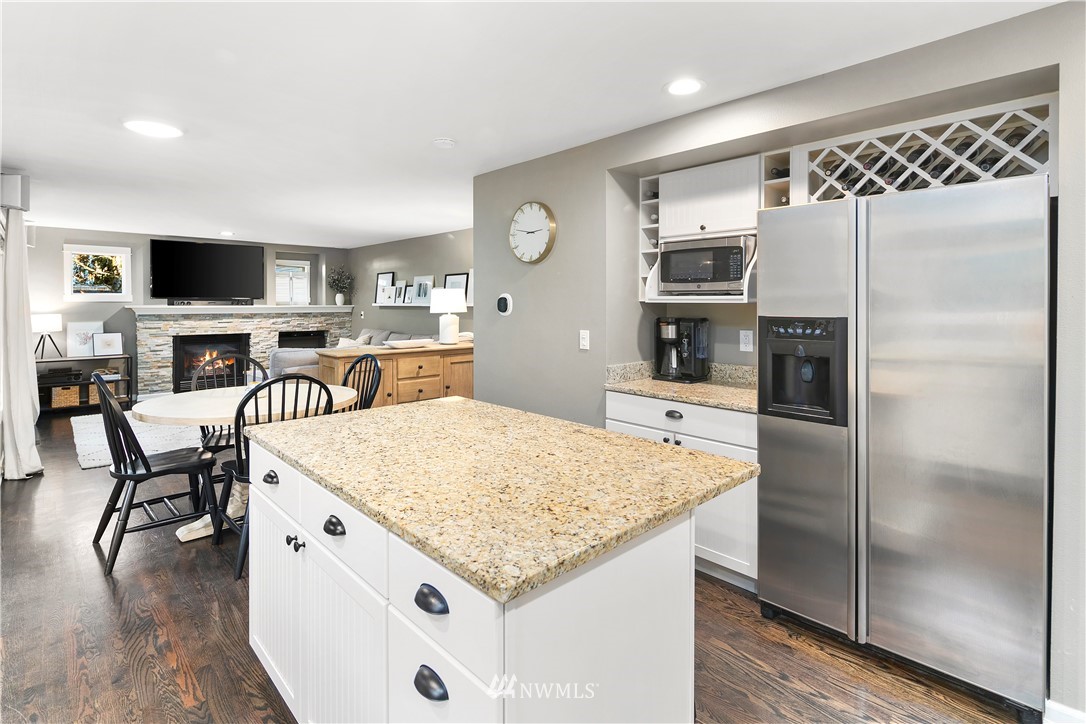 3121 210th Street Southeast Bothell, WA 98021 - Photo 14 of 40 a kitchen with a refrigerator a microwave a stove and a dining table with wooden floor