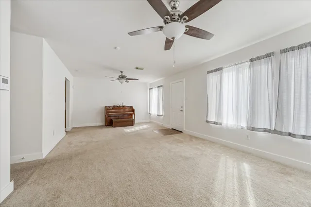 an empty room with a ceiling fan and windows