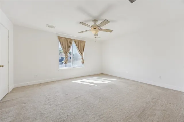 an empty room with windows and fan
