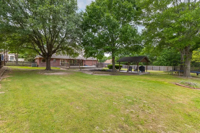 a view of a swimming pool with lawn chairs and large trees