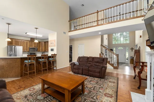 a living room with furniture a rug kitchen view and a large window