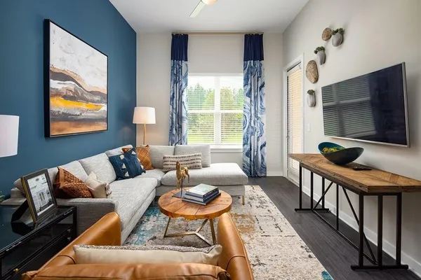 a living room with furniture a flat screen tv and a floor to ceiling window