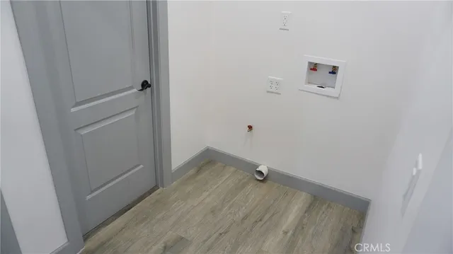 a view of an empty room with wooden floor and closet