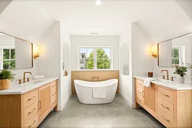 a spacious bathroom with a double vanity sink a large mirror and a bathtub