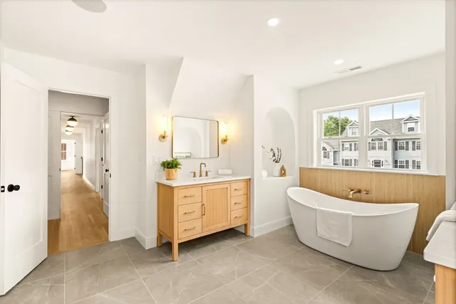 a spacious bathroom with a tub sink and mirror