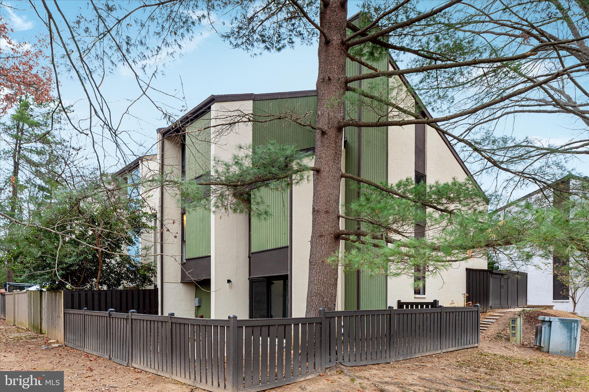 11608 Newbridge Court Reston, VA 20191 - Photo 46 of 47 a view of a brick house with large trees and wooden fence
